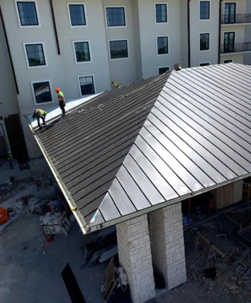 Crew installing standing seam metal roof panels on a commercial project in Pascagoula